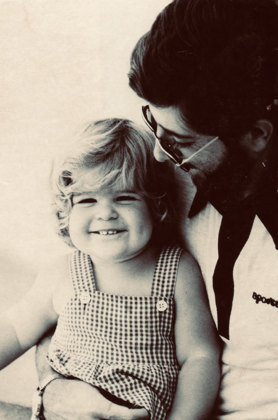A young Andrea, smiling, with her father — a tender vintage portrait.